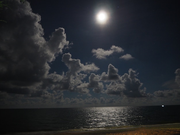 Cielo nocturno con luna llena y reflejo en el mar, hermosas nubes