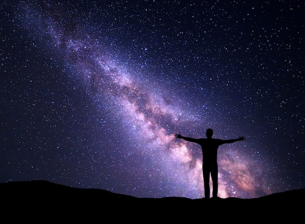 Cielo nocturno con la Vía Láctea y la silueta de un hombre