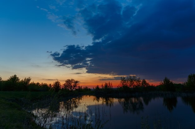 El cielo con nubes brillantes iluminadas por el sol después del atardecer sobre el lago.