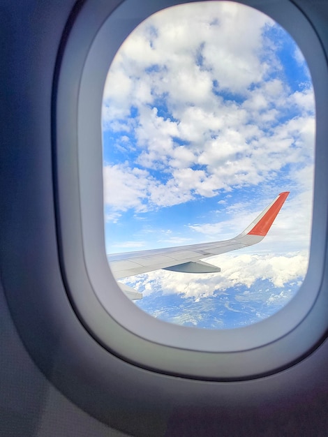 Cielo nublado azul con el ala del avión visto fuera de la ventana.