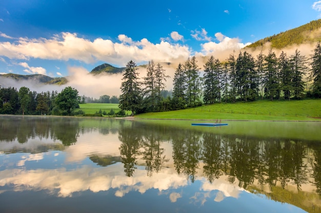 Cielo de reflexión y árboles en un lago tranquilo en las montañas de los Alpes hermoso paisaje matutino