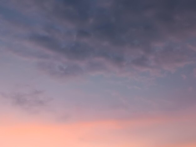 Un cielo rosa y azul con nubes y un avión en el cielo.