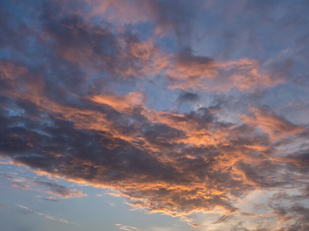 Cielo de la tarde con nubes azules, blancas y naranjas.