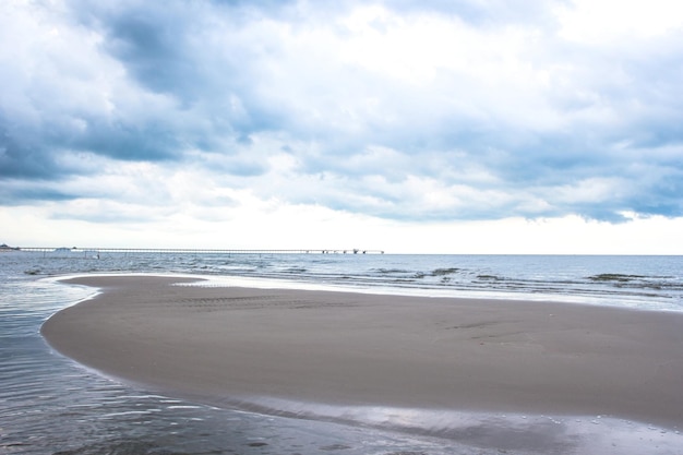 Cielo tormentoso sobre arena oscura y mar