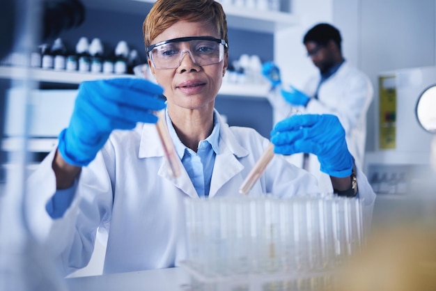 Ciência da mulher negra e tubo de ensaio em laboratório para estudo médico de pesquisa ou experimento de laboratório cientista de saúde feminina com medicamento de amostra líquida farmacêutica ou frascos no desenvolvimento de vacinas