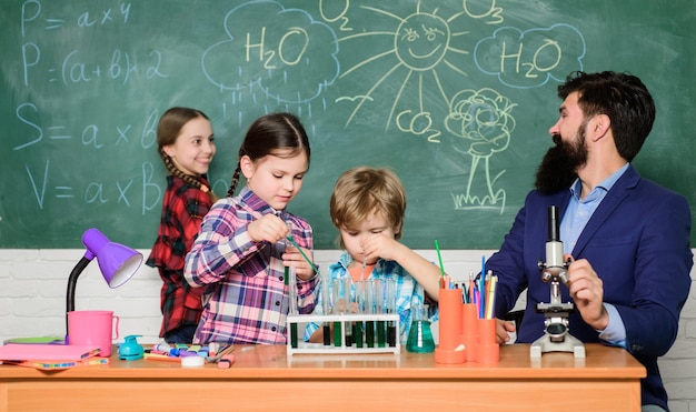 La ciencia es siempre la solución Observar la reacción Experimento de química escolar Lección de química fascinante Profesor barbudo y alumnos con tubos de ensayo en el aula Explicando química a los niños