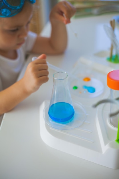 Ciencia Pequeña niña linda establece experimentos en casa líquidos de color laboratorio instalación de niños