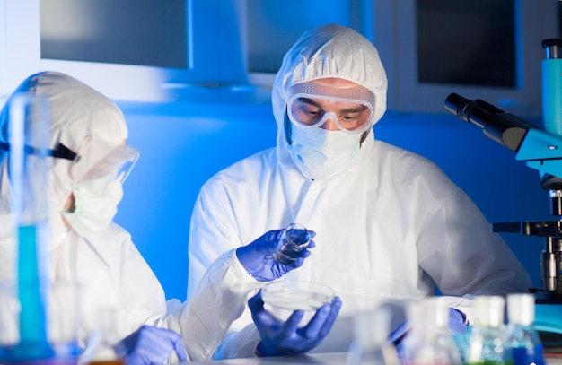 ciência, química e conceito de pessoas - close-up de cientistas com amostras químicas em placa de petri fazendo teste ou pesquisa em laboratório