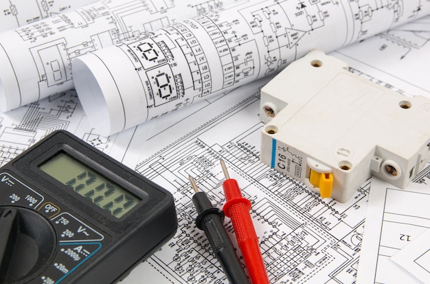 Ciencia, tecnología y electrónica. Impresión de planos de ingeniería eléctrica con disyuntor y mulyimeter. Desarrollo científico.