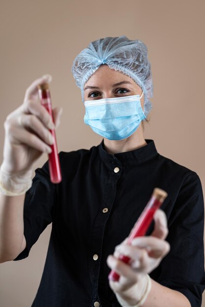 Foto científica caucásica en uniforme negro con un tubo de ensayo de muestra de sangre