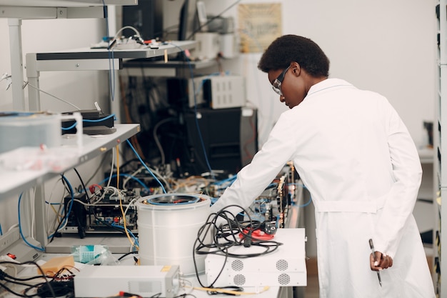 Foto científica mujer afroamericana que trabaja en laboratorio y criptografía de fibra óptica de codificador de decodificador de fotón único.