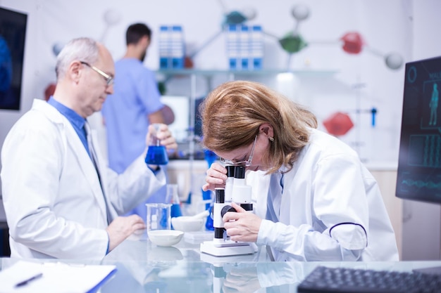 Científica senior que trabaja en un laboratorio contra enfermedades. Científico masculino senior con un tubo de ensayo en la mano.