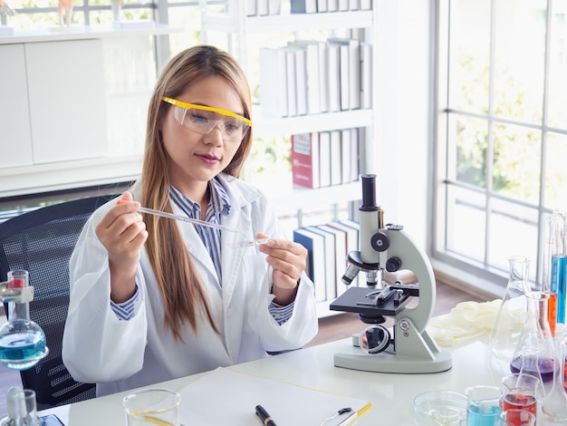 Científico asiático trabajando en laboratorio con microscopio