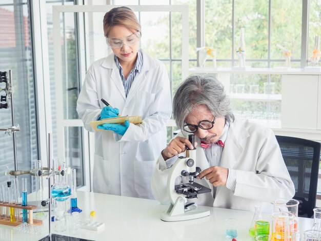 Científico asiático trabajando en laboratorio con microscopio