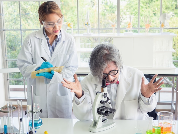 Científico asiático trabajando en laboratorio con microscopio