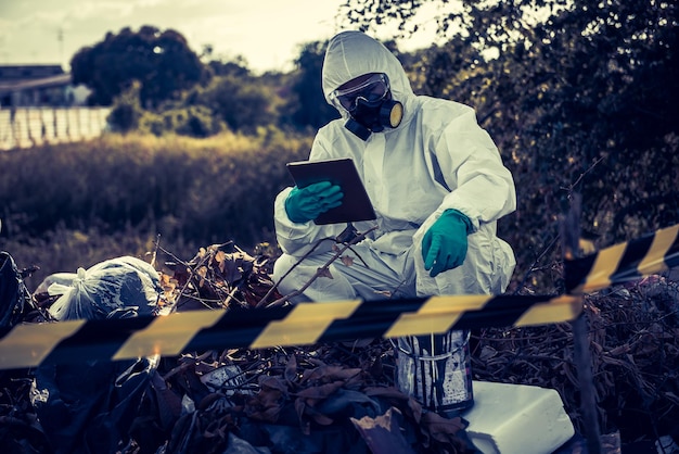 Científico asiático usa traje de protección química verifica el peligro químico trabajando en zonas peligrosas autenticando los químicos peligrosos