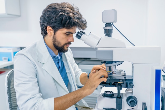 Científico concentrado trabajando con microscopio en laboratorio