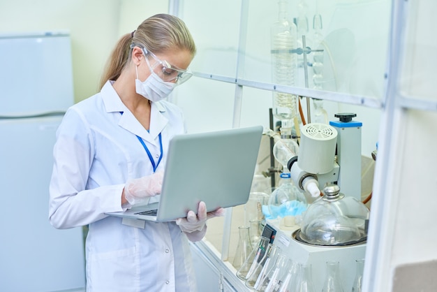 Científico femenino usando laptop en laboratorio