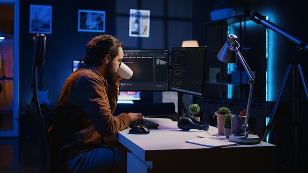Científico informático bebiendo una taza de café mientras desarrolla código en la PC