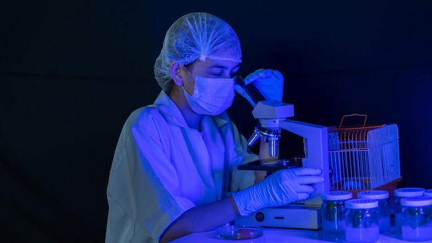 Científico de investigación médica femenina mirando a través del microscopio Microscopio científico en laboratorio Científico femenino está analizando moléculas de muestra con microscopio en laboratorio