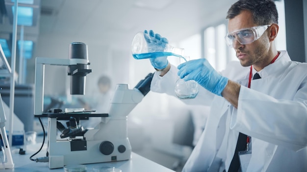 Un científico en un laboratorio con gafas protectoras y una bata de laboratorio está mirando en un microscopio.