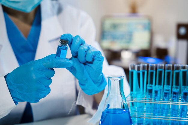 Científico médico o investigador o médico que mira un tubo de ensayo de solución clara en un laboratorio o laboratorio
