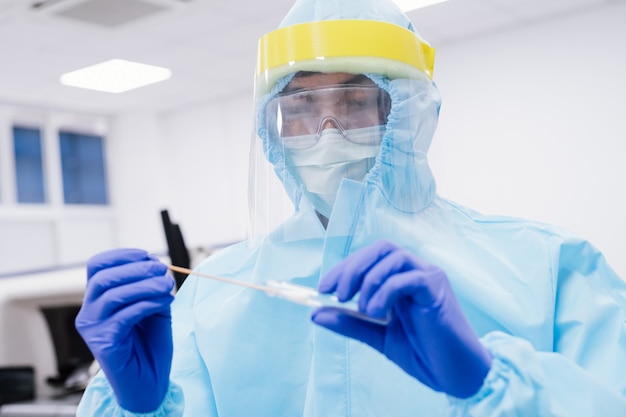 Foto científico médico en uniforme de traje ppe con hisopo de prueba de coronavirus en laboratorio