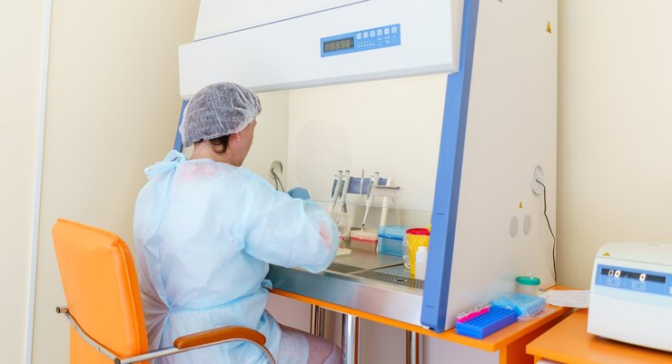 Científico o asistente de laboratorio con gotero o pipeta, examinando muestras y líquido para la investigación del ADN.