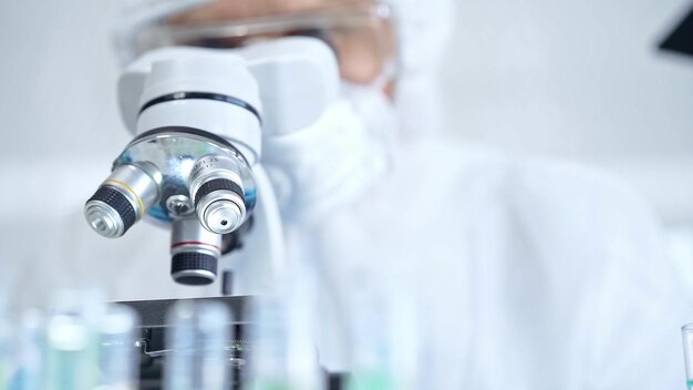Científico profesional con equipo de protección está usando el microscopio en un laboratorio de primer plano Conceptos de ciencia y medicina