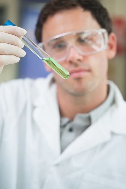 Científico que analiza la solución verde en el tubo de ensayo en el laboratorio