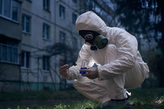 Científico que investiga al aire libre con un mono blanco y una máscara de gas