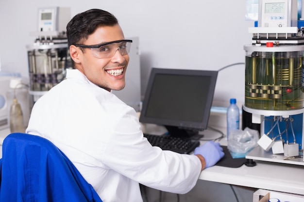 Foto científico sonriente que trabaja con la computadora