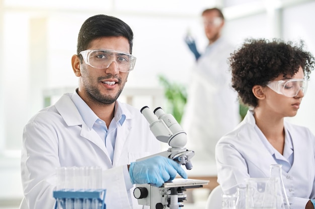 Científico sonriente sentado frente a un microscopio de laboratorio