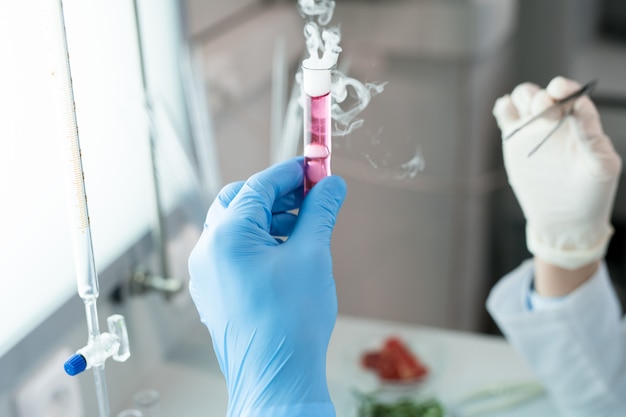 Científico sosteniendo fumar tubo de ensayo rosa