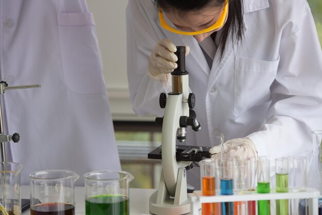 Científico con su colega usando el microscopio en el laboratorio
