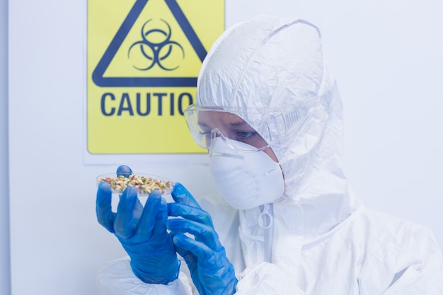 Científico en traje de protección con brotes en laboratorio