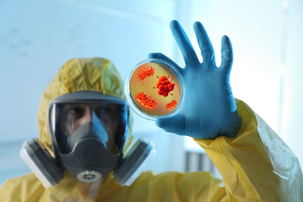 Foto científico en traje de protección química con placa de petri en laboratorio virus de la viruela del mono