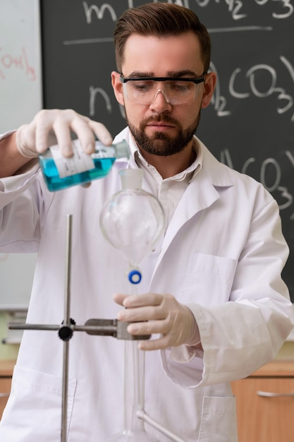 Foto el científico está vertiendo sustancia en el condensador de un laboratorio