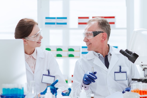 científicos discutiendo muestras sentados en una mesa de laboratorio