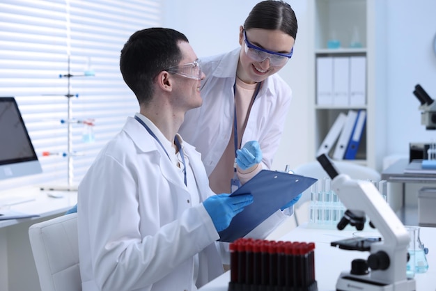 Científicos que trabajan con formularios de pruebas de laboratorio en una mesa en interiores
