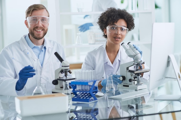 Científicos sonrientes mirando a la cámara con los brazos cruzados en el laboratorio