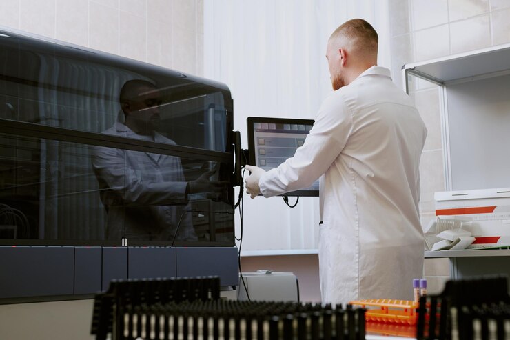 Foto cientista a trabalhar num ambiente de laboratório estéril a rever dados no ecrã do computador durante a operação
