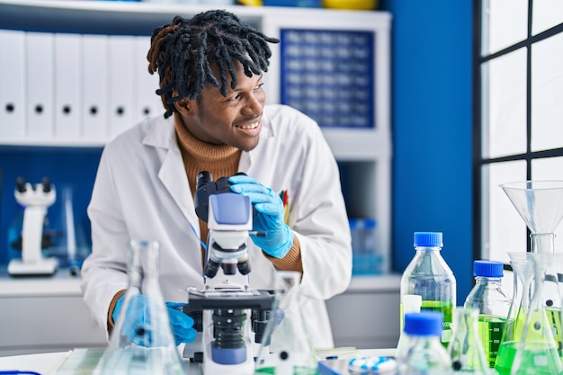 Cientista afro-americano usando microscópio no laboratório