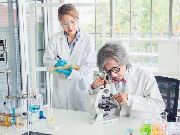 Cientista asiática trabalhando em laboratório com microscópio