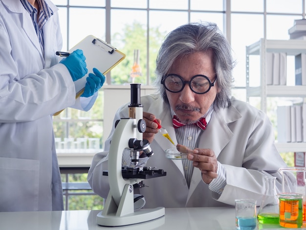 Cientista asiática trabalhando em laboratório com microscópio