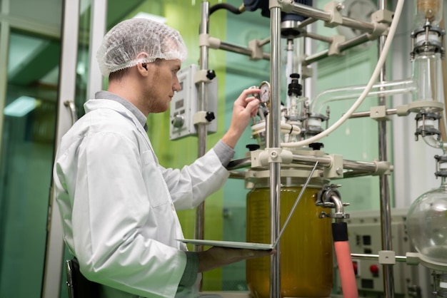 Cientista Boticário registrando dados do extrator de óleo CBD em laboratório