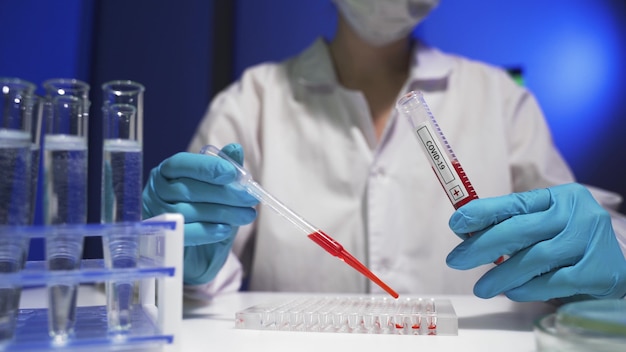 Cientista da suíte PPE fazendo pesquisas, verificando um líquido em um tubo de ensaio em laboratório.