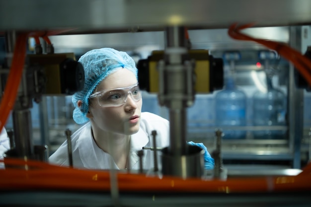 Cientista de casaco branco e chapéu azul trabalhando na máquina de controle da linha de produção.