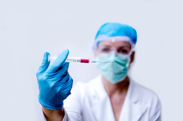 Cientista de mulher segurando a seringa com amostra de sangue com o vírus Covid-19. Trabalhando com a vacina de proteção contra vírus. Exposição dupla do mapa do mundo. Pesquisa em laboratório médico