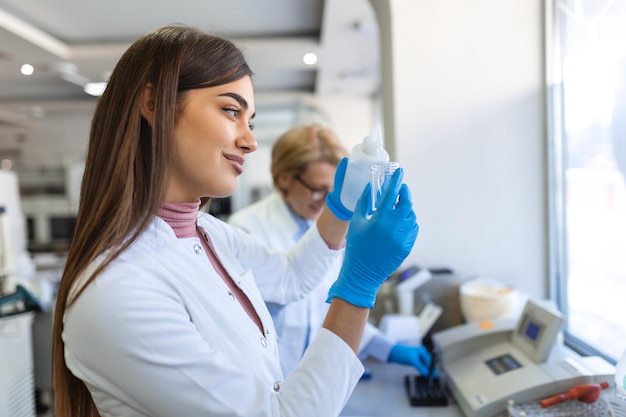 Cientista de pesquisa médica feminina analisa amostras biológicas antes de analisá-las sob o microscópio digital no laboratório de ciências aplicadas Engenheiro de laboratório em jaleco branco trabalhando em vacinas e remédios